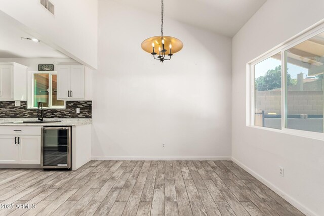 2109 E Gelding Dr, Phoenix, AZ 85022 - kitchen with beverage cooler, light wood-style floors, tasteful backsplash, light countertops, and white cabinetry
