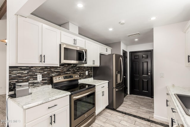 2109 E Gelding Dr, Phoenix, AZ 85022 - kitchen with stainless steel appliances, backsplash, wood finish floors, white cabinetry, and recessed lighting