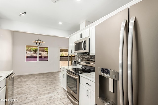 2109 E Gelding Dr, Phoenix, AZ 85022 - kitchen with appliances with stainless steel finishes, decorative backsplash, white cabinets, hanging light fixtures, and light wood-style floors
