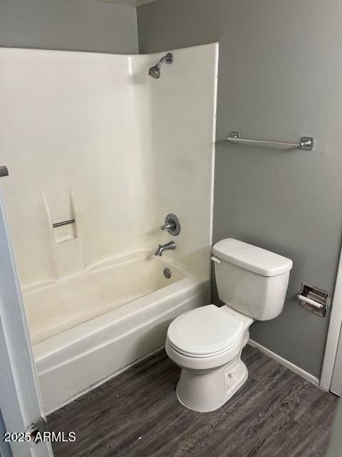 bathroom featuring bathing tub / shower combination, wood finished floors, and toilet