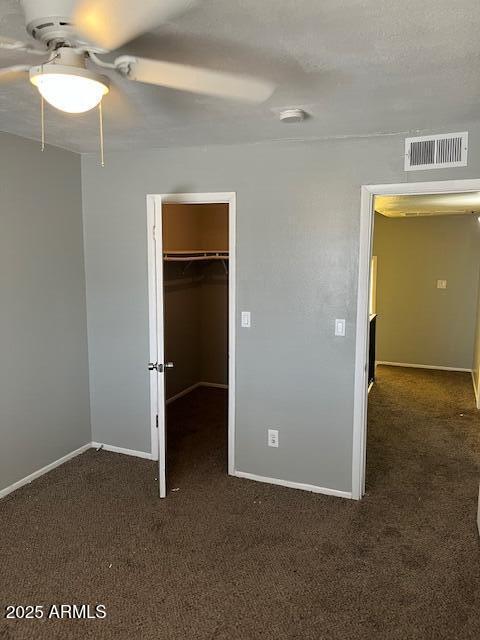 unfurnished bedroom featuring carpet floors, visible vents, baseboards, a spacious closet, and a closet