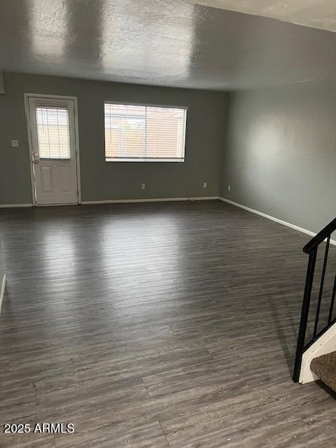 interior space with dark wood-type flooring, a textured ceiling, and baseboards