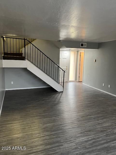 unfurnished living room featuring stairway, wood finished floors, and baseboards