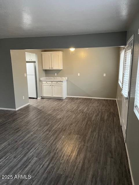 unfurnished living room with dark wood finished floors and baseboards