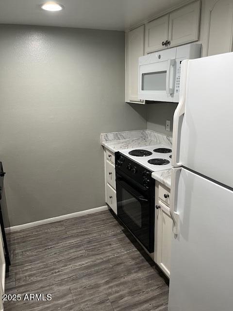 kitchen with white appliances, white cabinetry, baseboards, light countertops, and dark wood finished floors