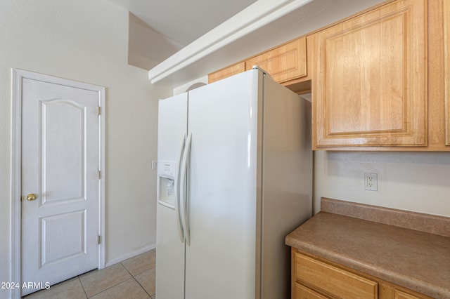 kitchen featuring white fridge with ice dispenser, light tile patterned flooring, and light brown cabinetry