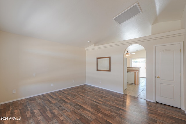 empty room with vaulted ceiling, dark hardwood / wood-style floors, and ceiling fan