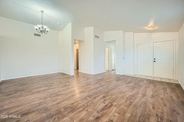 unfurnished room with an inviting chandelier, wood-type flooring, and high vaulted ceiling