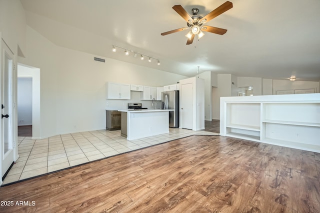 kitchen featuring ceiling fan, appliances with stainless steel finishes, white cabinetry, a center island, and light hardwood / wood-style floors