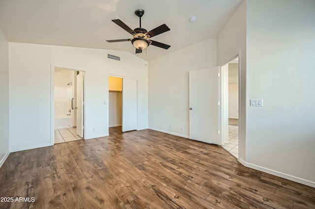 unfurnished bedroom with ensuite bath, vaulted ceiling, a closet, ceiling fan, and hardwood / wood-style floors