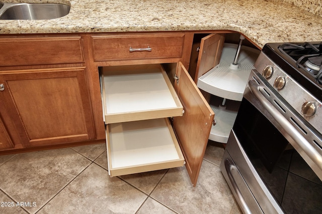 interior details with light stone counters, sink, and stainless steel range with gas stovetop