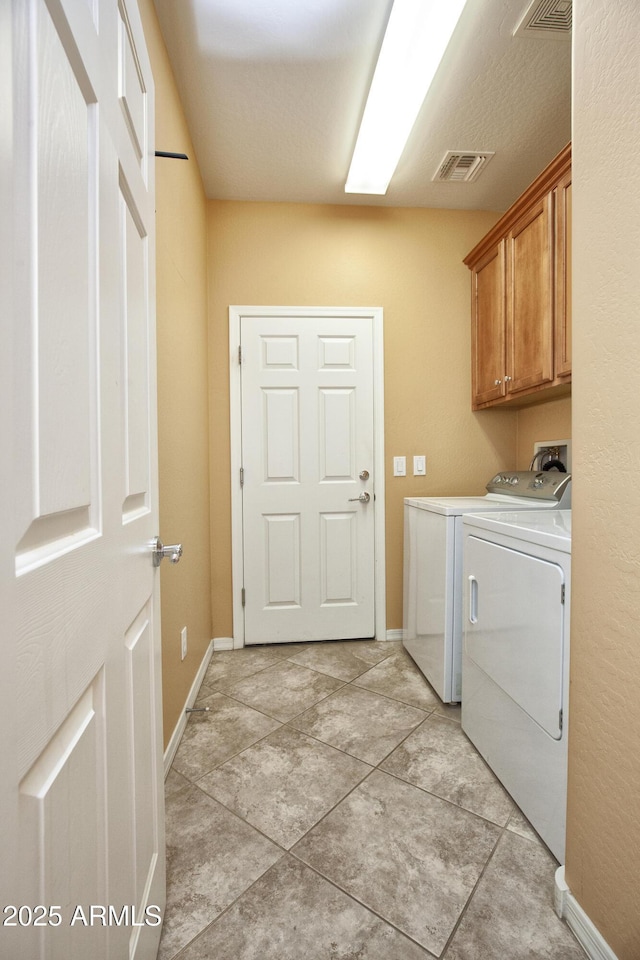 laundry room with cabinets, light tile patterned floors, and washer and dryer