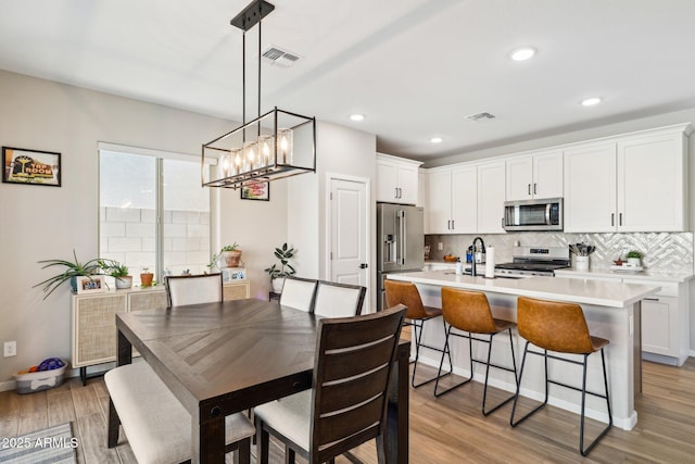 dining area featuring sink, light hardwood / wood-style flooring, and a notable chandelier