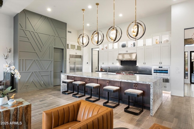 26690 N 119th St, Scottsdale, AZ 85262 - kitchen featuring a towering ceiling, stainless steel appliances, wood finish floors, tasteful backsplash, and under cabinet range hood
