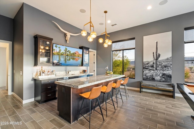 26690 N 119th St, Scottsdale, AZ 85262 - interior space featuring visible vents, a center island, glass insert cabinets, a sink, and a kitchen breakfast bar