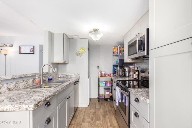 kitchen featuring white cabinets, light hardwood / wood-style flooring, sink, light stone countertops, and appliances with stainless steel finishes