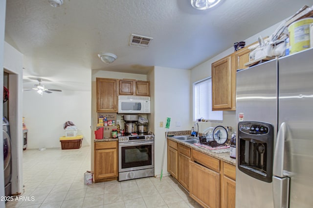 kitchen with visible vents, a sink, a textured ceiling, stainless steel appliances, and ceiling fan