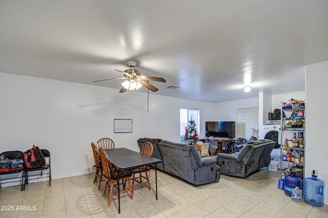 dining space featuring visible vents, light tile patterned flooring, a textured ceiling, washer / clothes dryer, and a ceiling fan