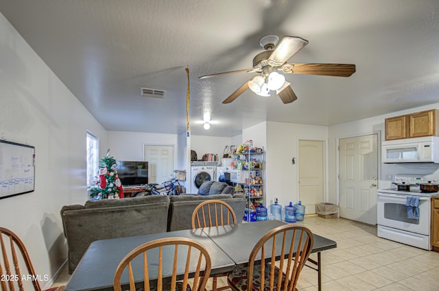 dining room with visible vents, a textured ceiling, washing machine and dryer, light tile patterned floors, and ceiling fan