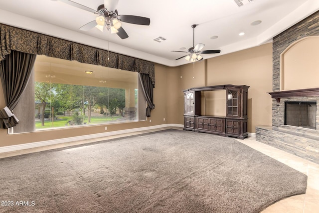 unfurnished living room featuring ceiling fan, carpet floors, a fireplace, and baseboards