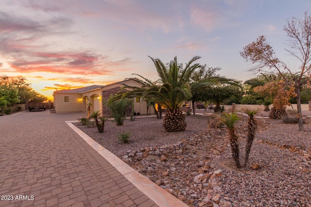 view of front facade featuring decorative driveway, fence, and stucco siding