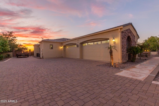 garage with central AC unit and decorative driveway