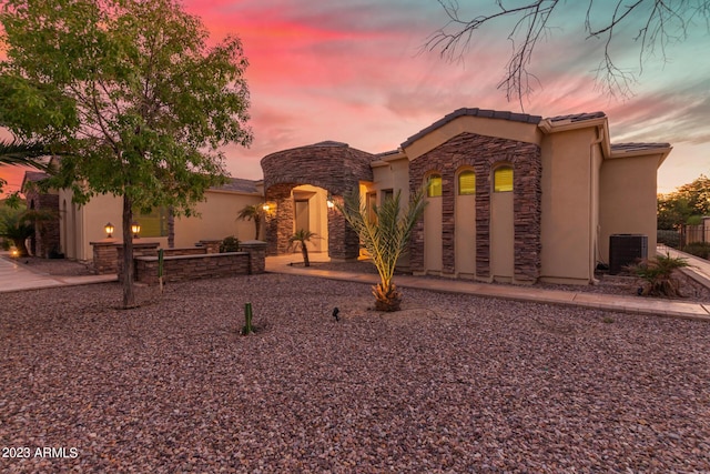 view of front of property featuring stone siding, central AC, and stucco siding