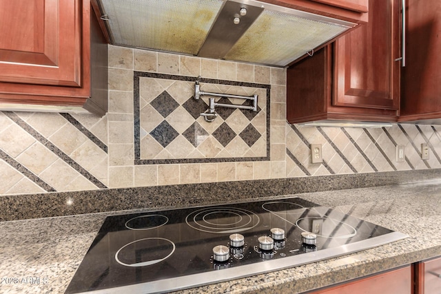 kitchen featuring black electric stovetop, light stone counters, ventilation hood, backsplash, and reddish brown cabinets