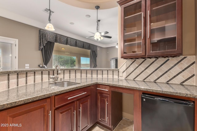 kitchen featuring visible vents, decorative backsplash, dishwashing machine, light stone countertops, and a sink