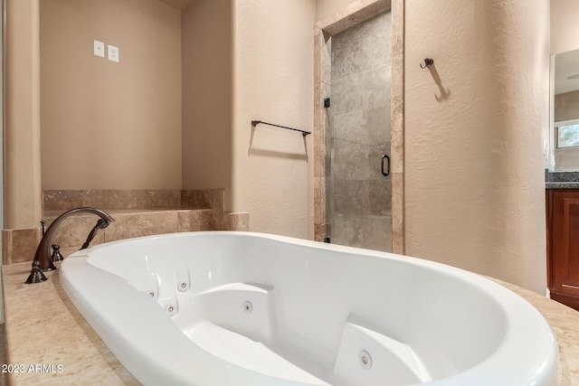 bathroom featuring a textured wall, a jetted tub, and vanity