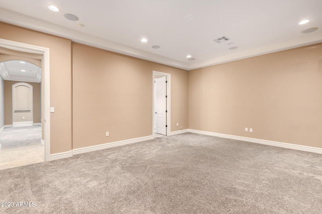 empty room featuring arched walkways, light carpet, baseboards, and recessed lighting