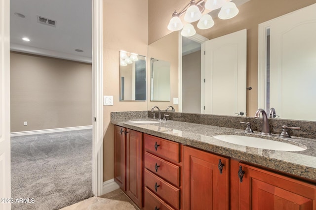 bathroom featuring double vanity, a sink, visible vents, and baseboards