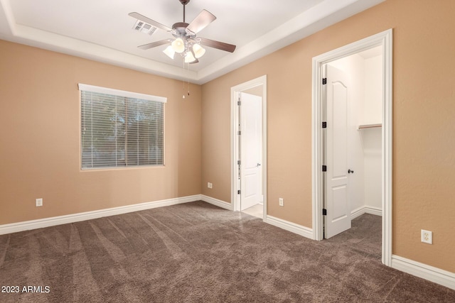 unfurnished bedroom featuring carpet floors, baseboards, visible vents, and a tray ceiling