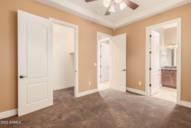 unfurnished bedroom featuring carpet floors, a spacious closet, and baseboards