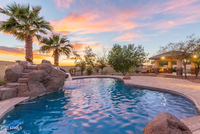 pool at dusk with a fenced in pool and a patio area