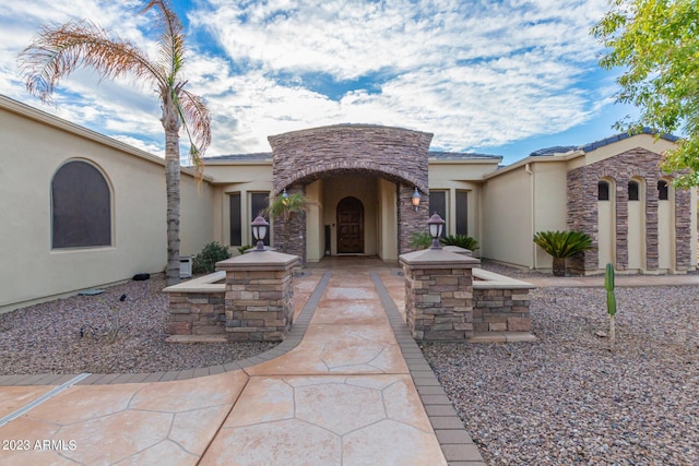 doorway to property featuring stone siding and stucco siding