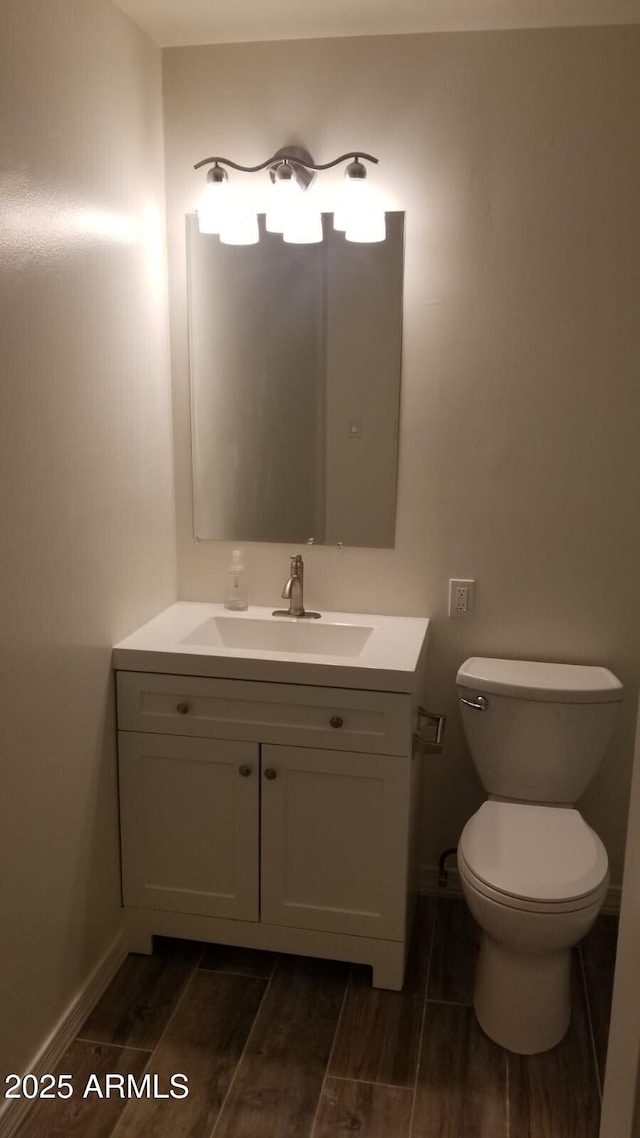 bathroom featuring wood tiled floors, vanity, toilet, and baseboards