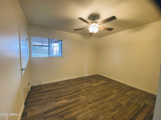 spare room featuring ceiling fan, dark wood finished floors, and baseboards