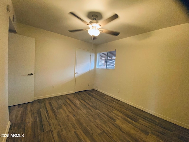 unfurnished room featuring a ceiling fan, dark wood finished floors, and baseboards