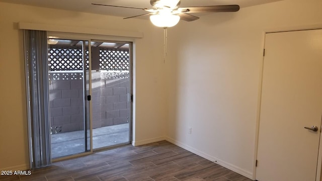 spare room featuring dark wood-style flooring, ceiling fan, and baseboards