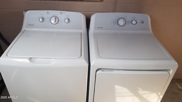 laundry room with washing machine and clothes dryer and concrete block wall