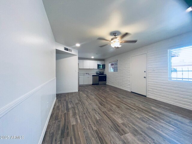 unfurnished living room featuring healthy amount of natural light, ceiling fan, dark wood-style floors, and baseboards