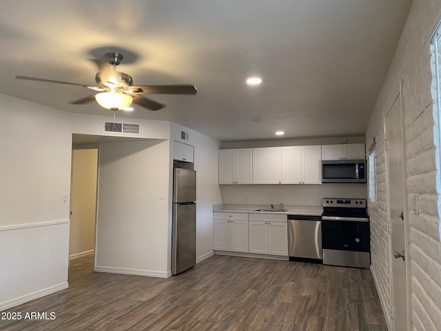 kitchen featuring appliances with stainless steel finishes, a sink, dark wood finished floors, white cabinetry, and recessed lighting