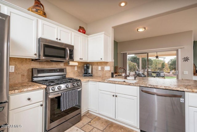 kitchen featuring appliances with stainless steel finishes, tasteful backsplash, sink, white cabinets, and light stone countertops