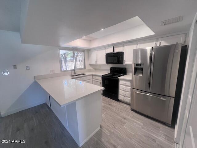 4332 W Ocotillo Rd Unit 206, Glendale, AZ 85301 - kitchen featuring black appliances, a tray ceiling, a peninsula, white cabinets, and light countertops