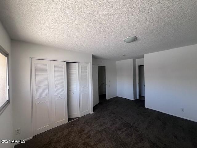 4332 W Ocotillo Rd Unit 206, Glendale, AZ 85301 - unfurnished bedroom featuring dark carpet, a closet, and a textured ceiling