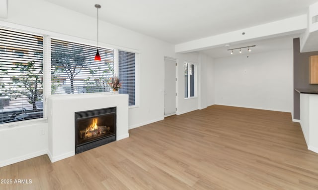 unfurnished living room featuring beamed ceiling and light hardwood / wood-style floors