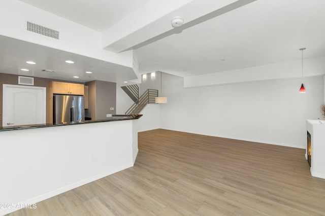 kitchen featuring light brown cabinetry, decorative light fixtures, stainless steel fridge, and light hardwood / wood-style floors