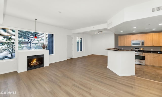 kitchen with rail lighting, light brown cabinets, light wood-type flooring, pendant lighting, and stainless steel appliances