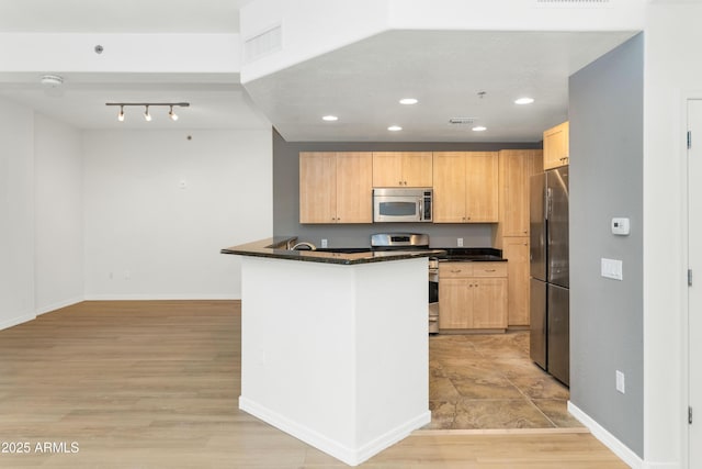 kitchen featuring stainless steel appliances, kitchen peninsula, light hardwood / wood-style floors, and light brown cabinets